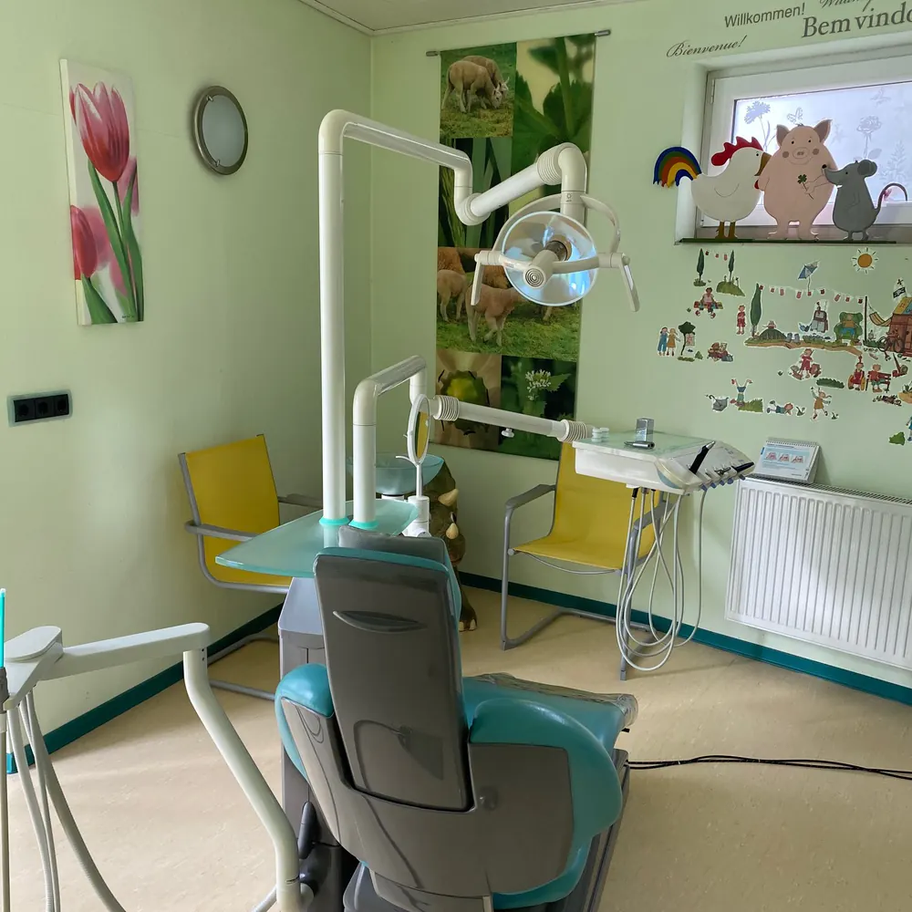 Helles Behandlungszimmer mit Tulpenbildern und Kinderbildern an der Wand
